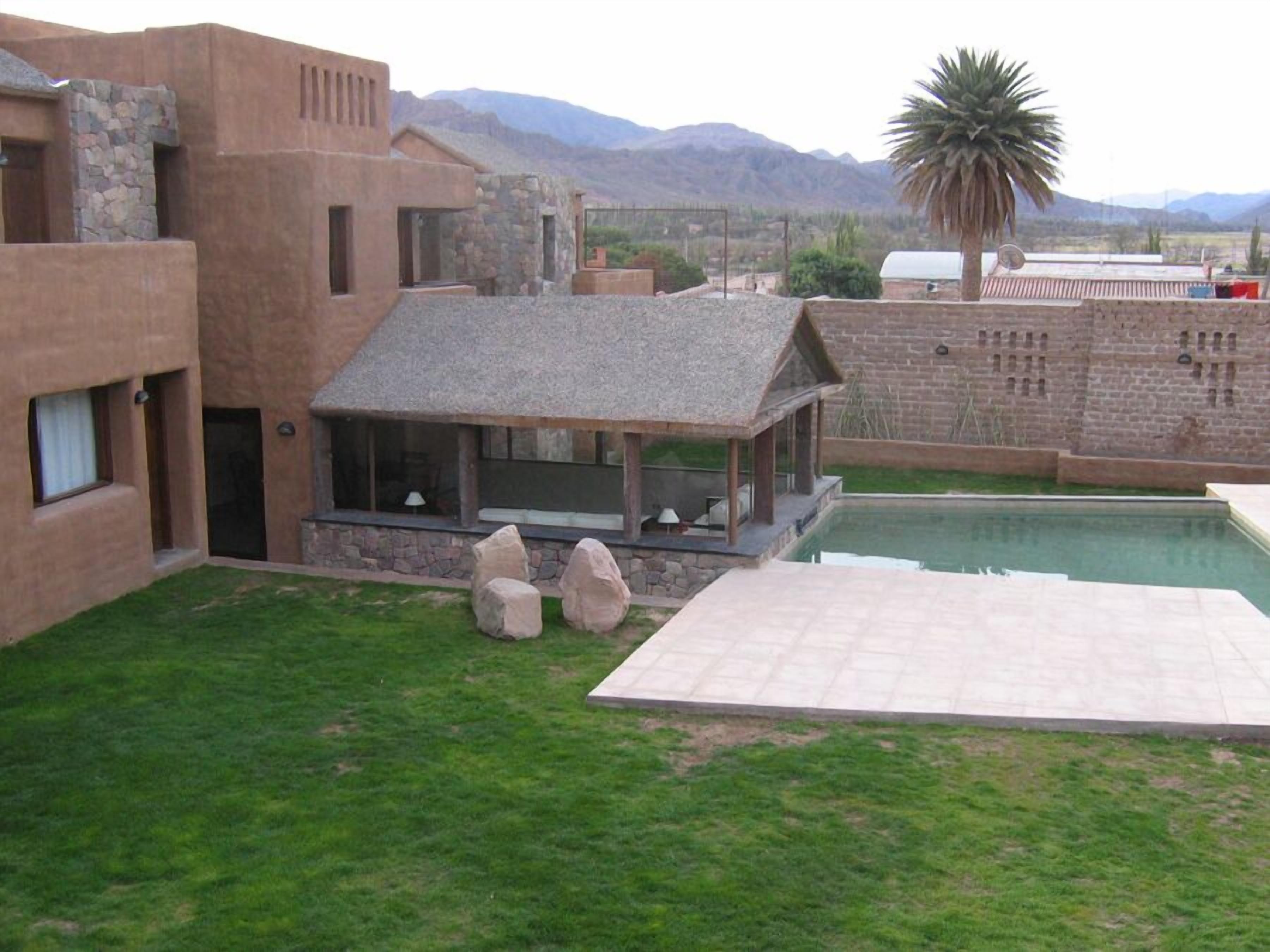 A pool area with a stone structure, a grassy lawn, and mountains in the background.