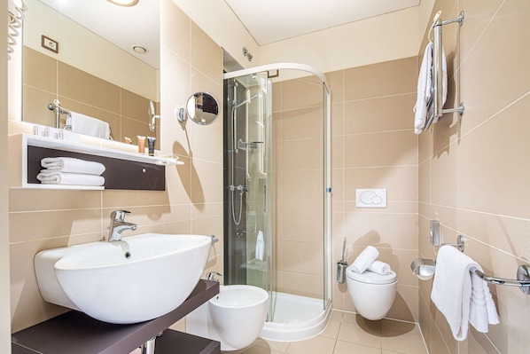A modern bathroom with a large white sink, a glass-enclosed shower, and a toilet with a towel rack.