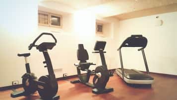 A room with three stationary bikes and a treadmill.