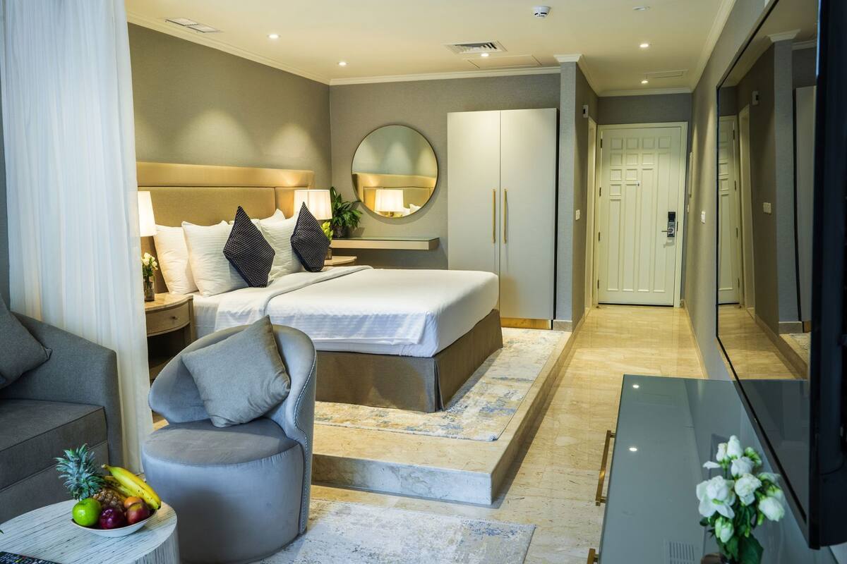 Een moderne hotelkamer met een bed, nachtkastje, lamp, spiegel, kledingkast en een televisie.