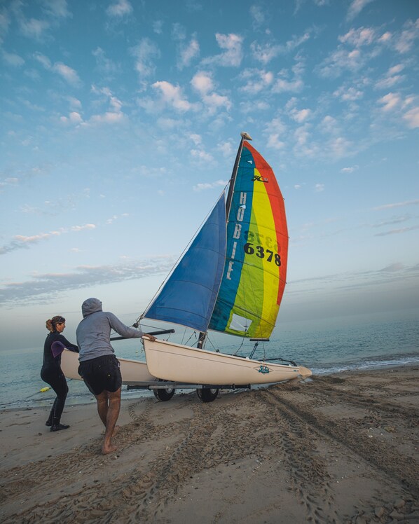 Un velero con vela de colores en una playa arenosa.