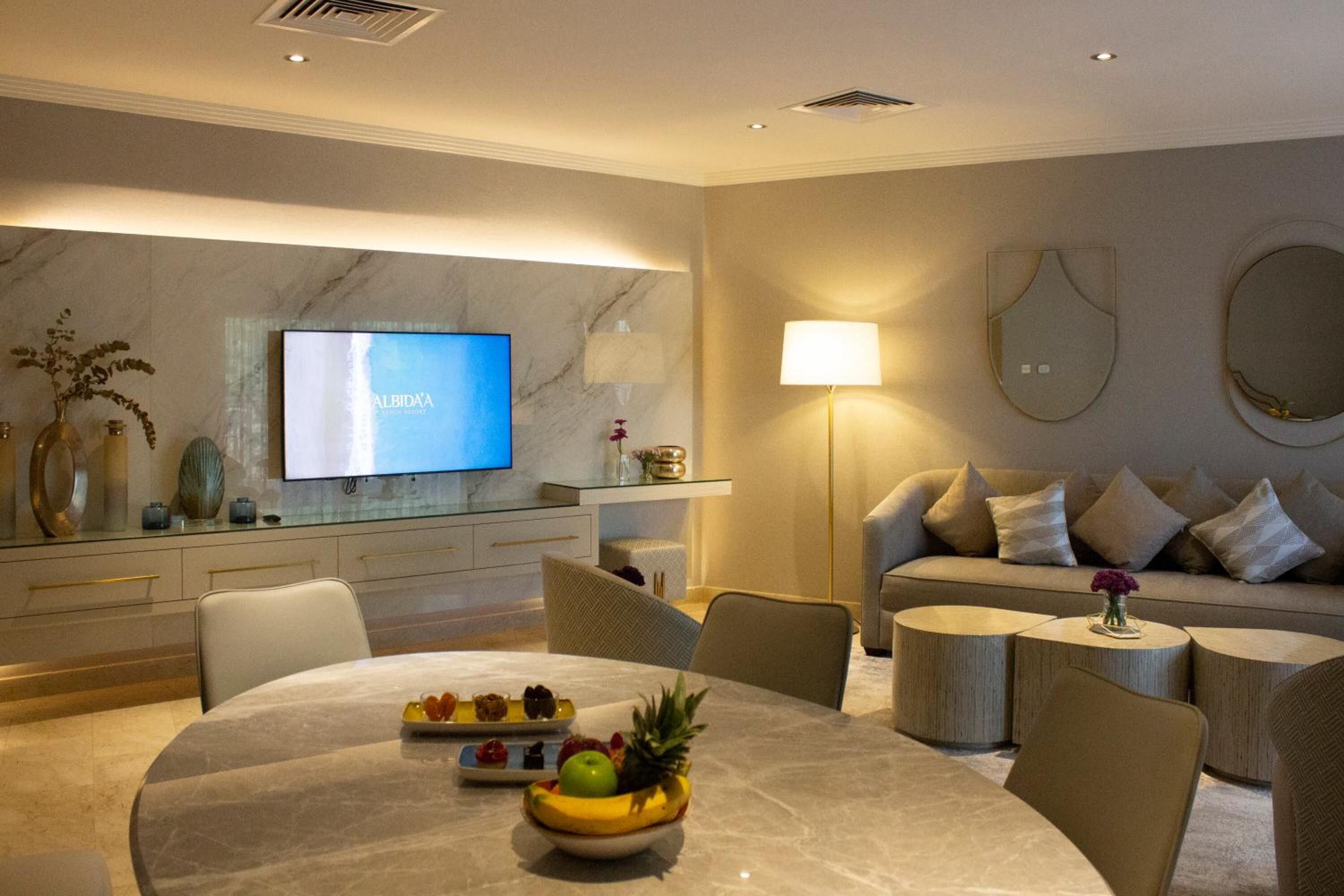 Ein modernes Wohnzimmer mit einem Marmortisch, einer Couch und einem an der Wand befestigten Fernseher.