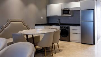 Una cocina moderna con zona de comedor, que incluye una mesa redonda, sillas, horno empotrado y refrigerador de acero inoxidable.