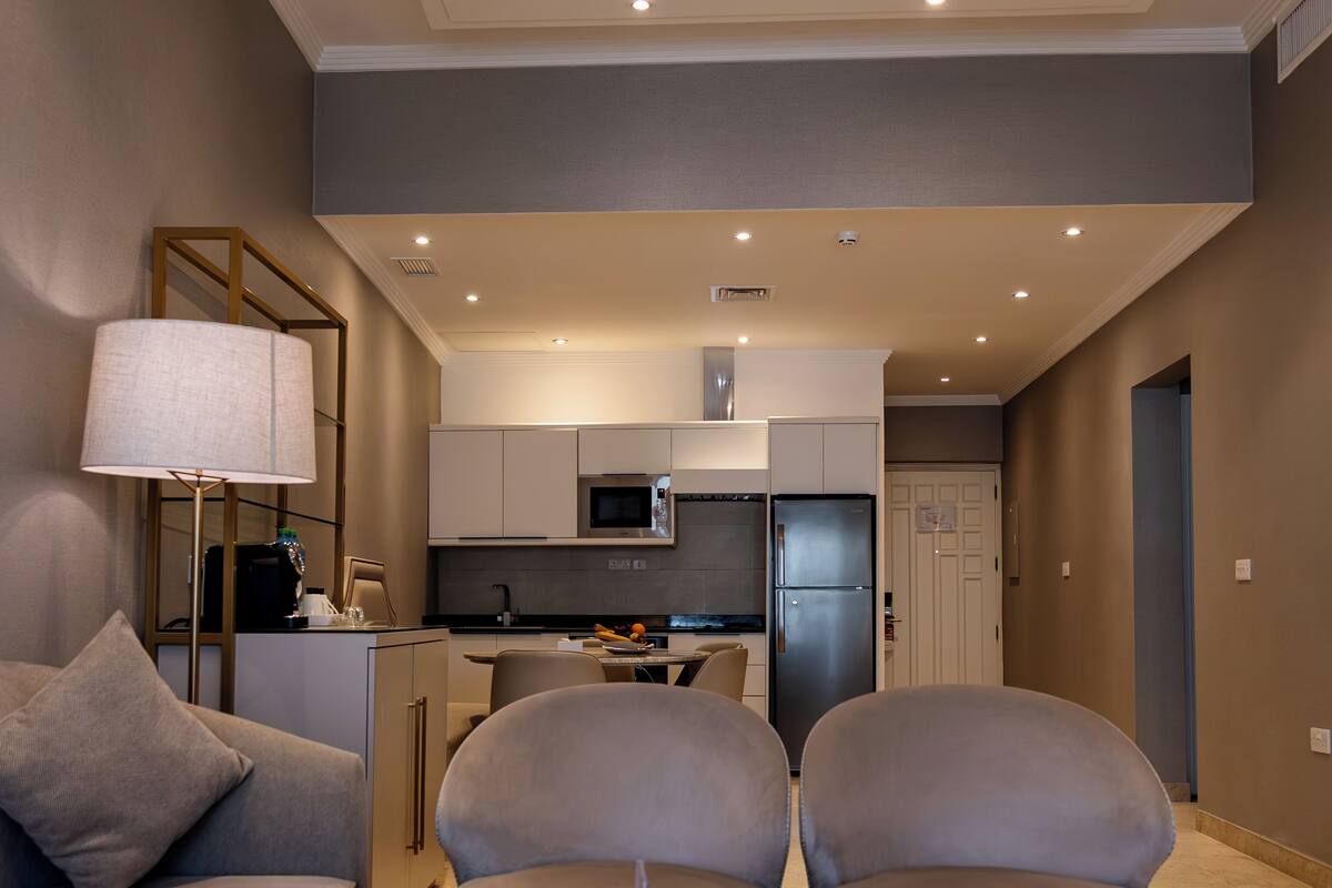 Een moderne woonkamer met een bank, twee fauteuils, een salontafel en een lamp.