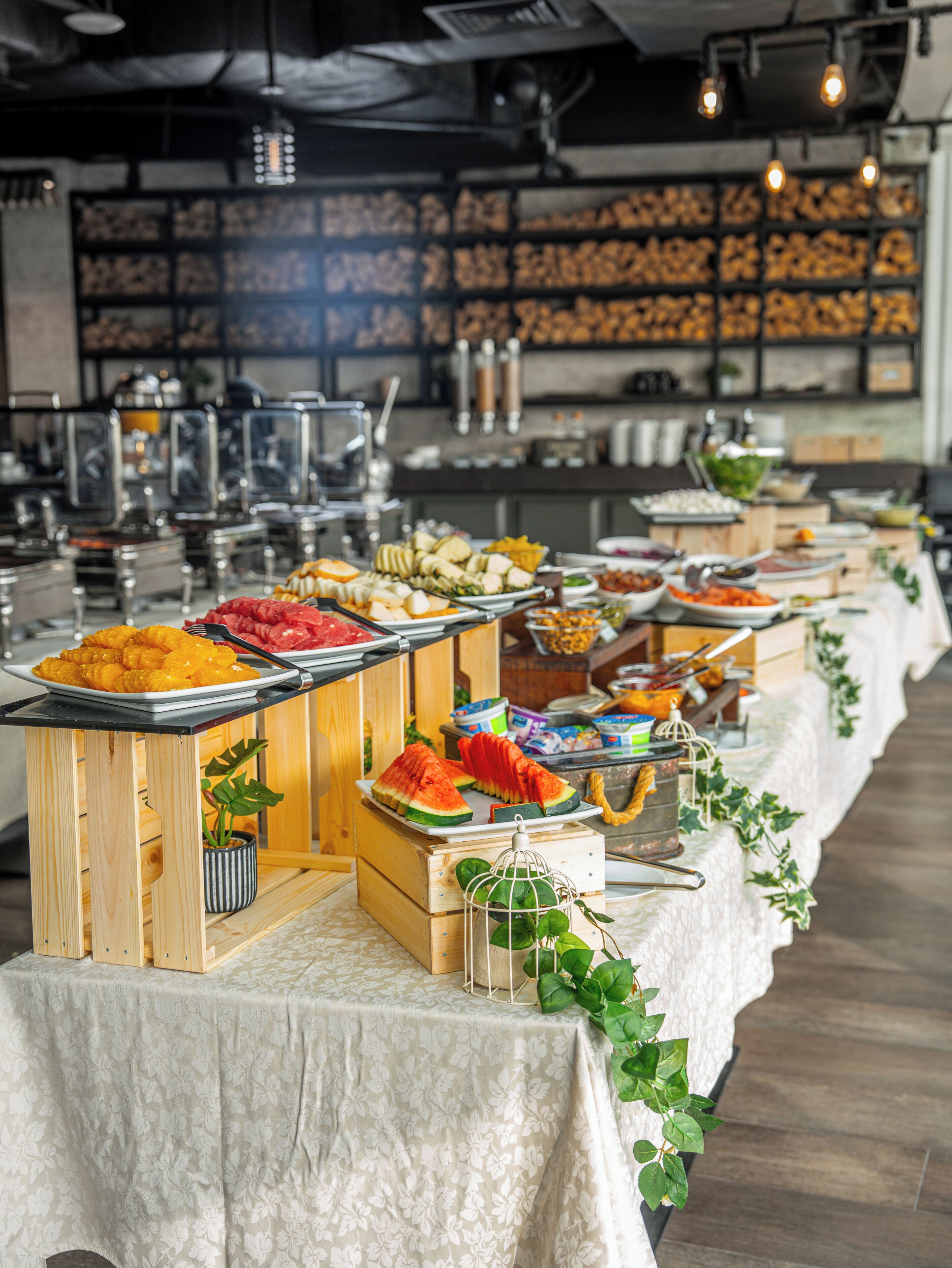 A buffet setup with various food items and a long table covered with a floral tablecloth.