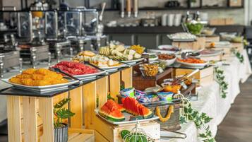 A buffet setup with various food items and a long table covered with a floral tablecloth.