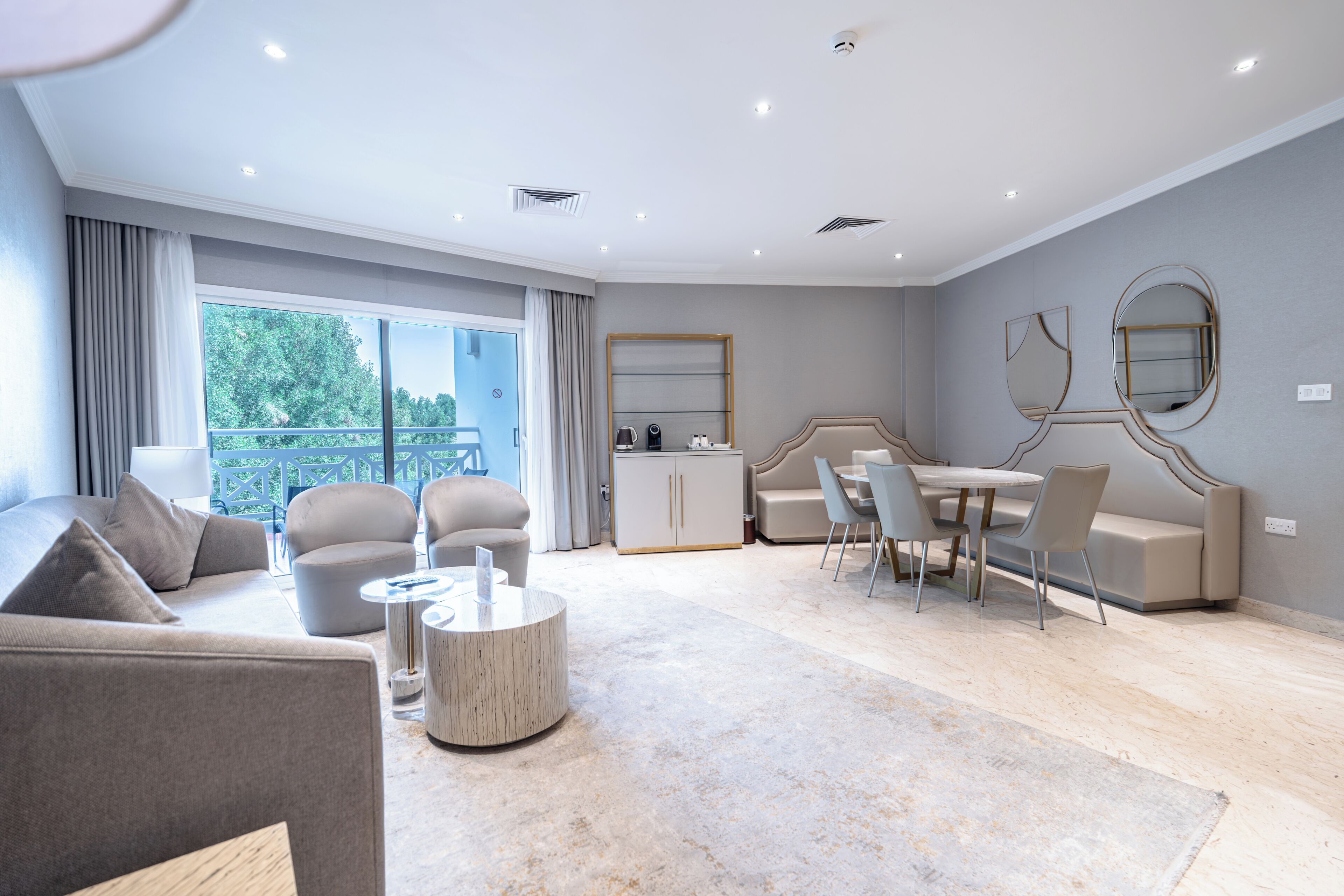 A modern living room with a sofa, chairs, a coffee table, and a dining area.