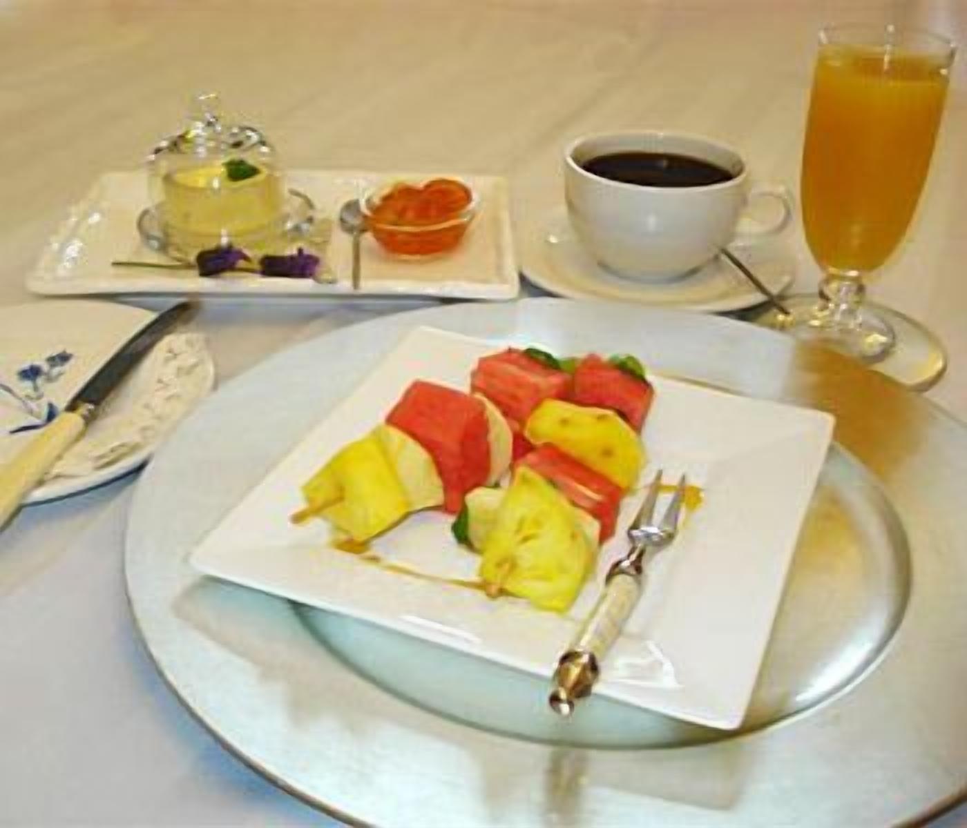 A breakfast setting with a plate of fruit, a cup of coffee, and a glass of orange juice.