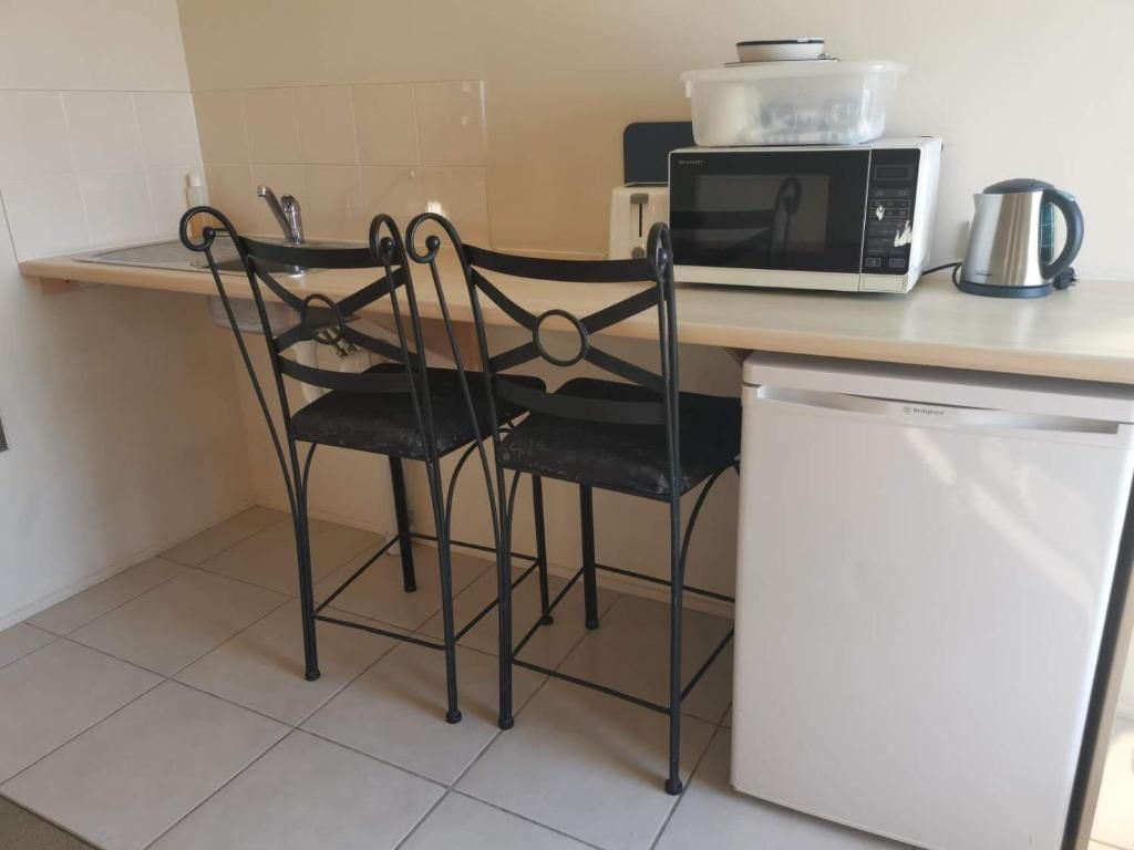 A kitchenette with a microwave, kettle, and a refrigerator.