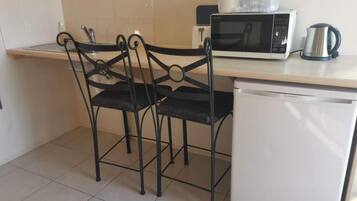 A kitchenette with a microwave, kettle, and a refrigerator.
