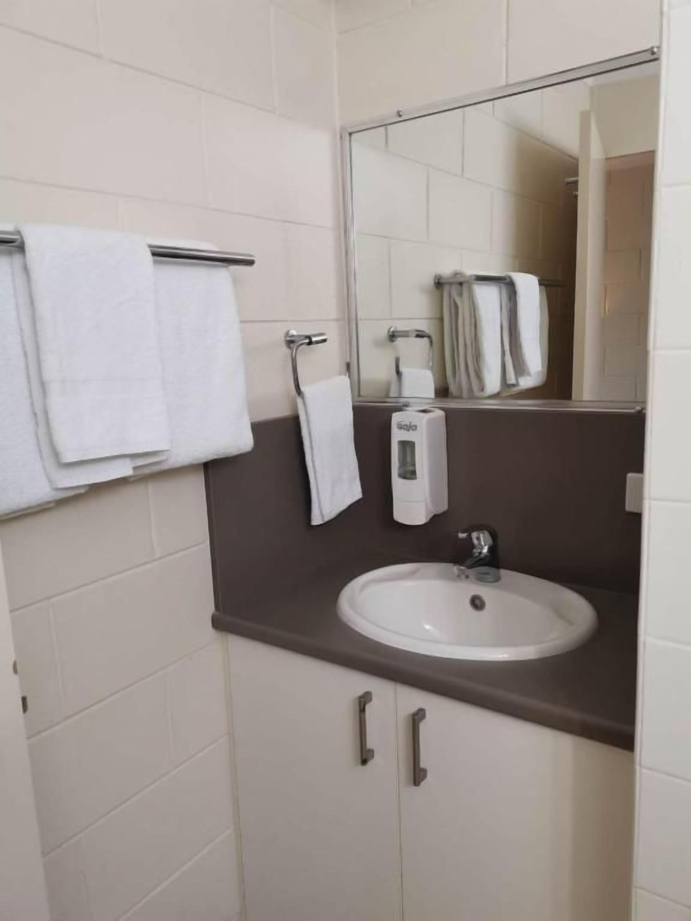 A bathroom with a white sink, a mirror, and a towel rack.