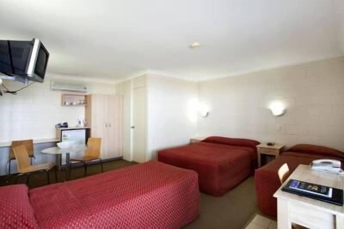 Habitación de hotel con cama, escritorio, silla y televisión.