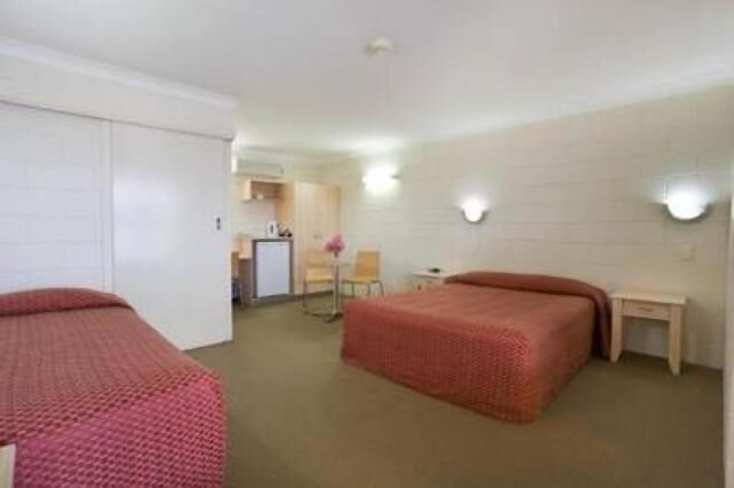 Una camera d'albergo con due letti, una scrivania, una sedia e un piccolo tavolino.