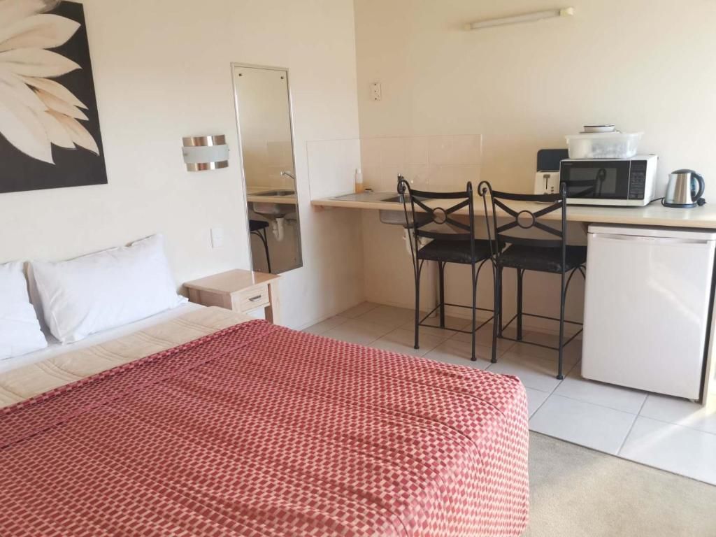 Une chambre d’hôtel de taille réduite, comprenant un lit, une petite kitchenette et un coin repas.
