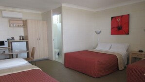A hotel room with two beds, a small kitchenette, a bathroom, and a red flower painting on the wall.