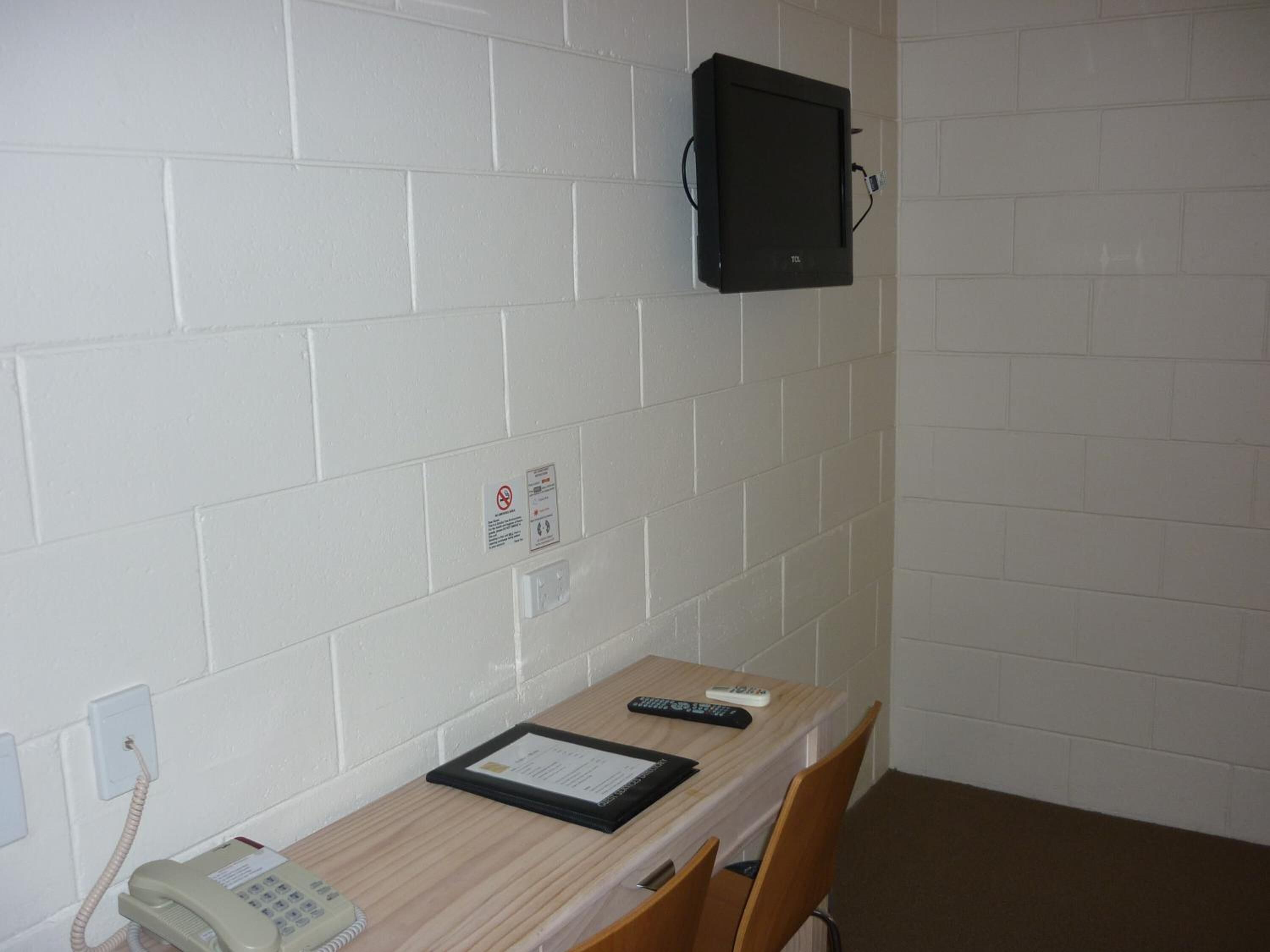 A small office with a desk, chair, telephone, and a mounted computer monitor.