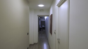 A narrow hallway with a wooden floor, white walls, and a door on the right. - Venere B&B (Catania)