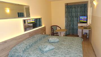 A hotel room with a bed, a desk with a computer, a chair, and a TV.