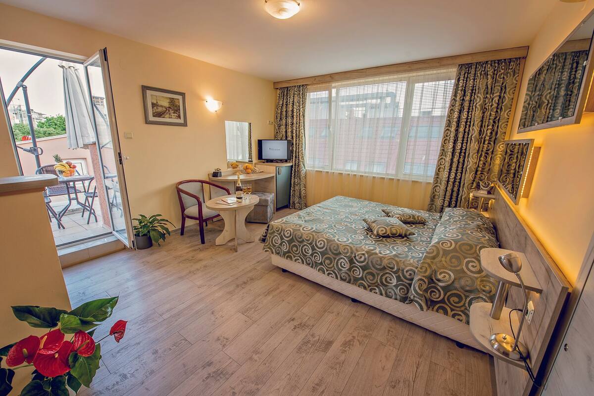 Una habitación de hotel con cama, escritorio, silla y televisor.