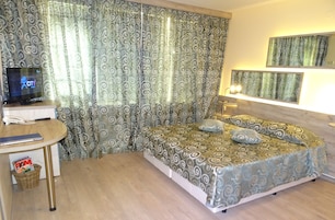 Una habitación de hotel con cama, escritorio, computadora, teléfono y cortinas.