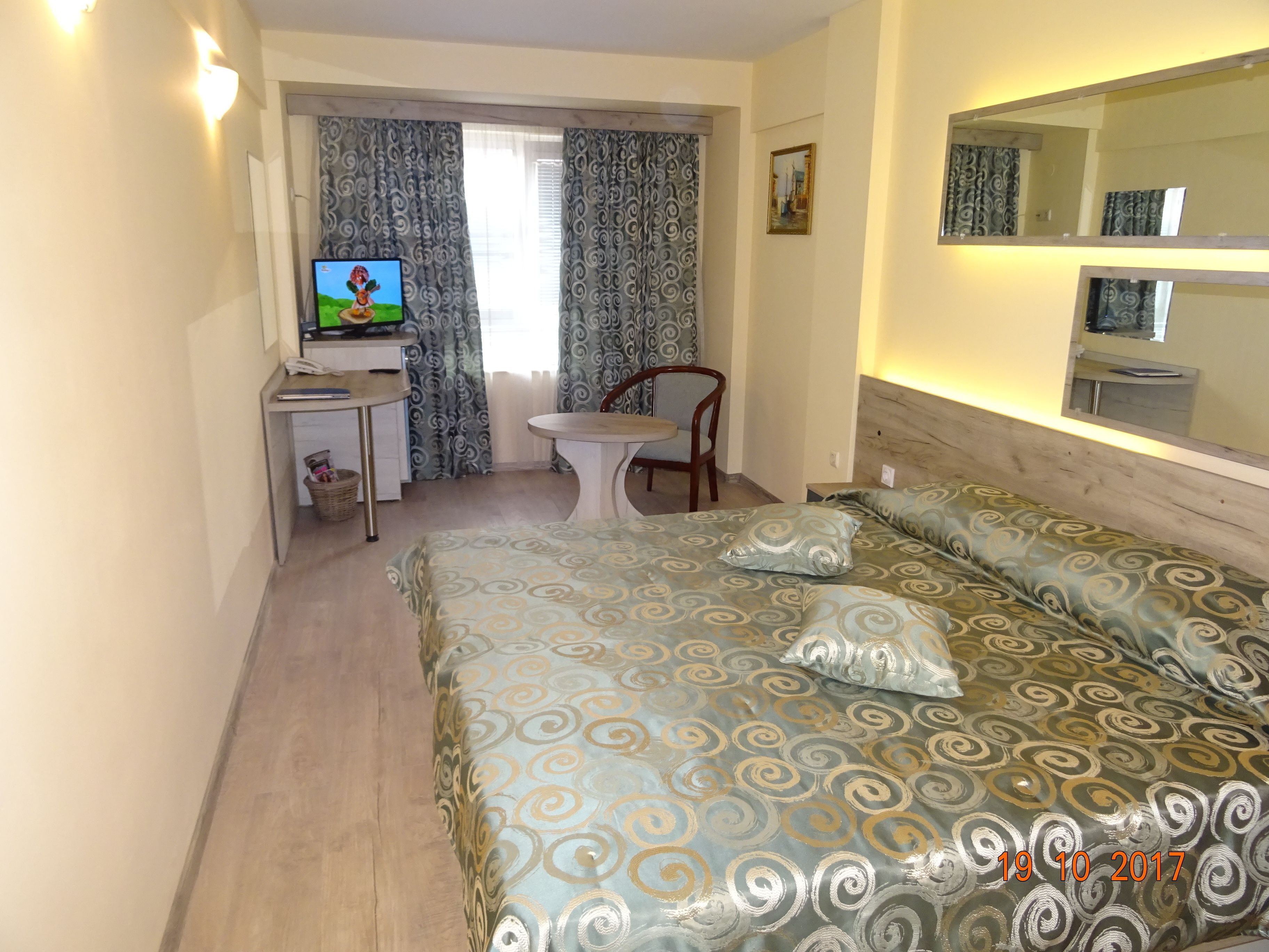 Una habitación de hotel con una cama, un escritorio con computadora, una silla y un televisor.