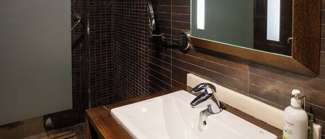 A modern bathroom with a large mirror, a wooden vanity, and a shower area.