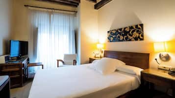 Une chambre d’hôtel avec un grand lit, un bureau avec une télévision, une chaise et deux lampes de chevet.