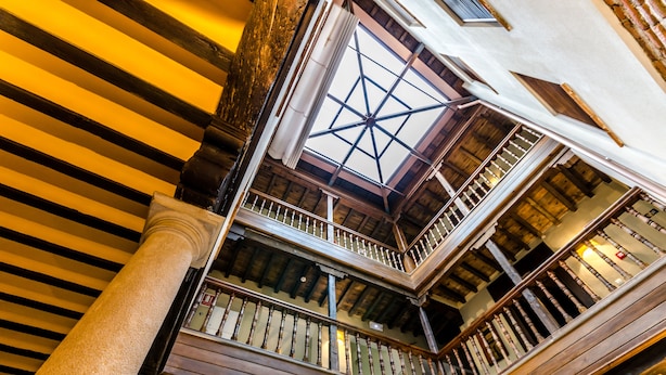 Una escalera de madera de varios niveles con techo de cristal y vista al interior.