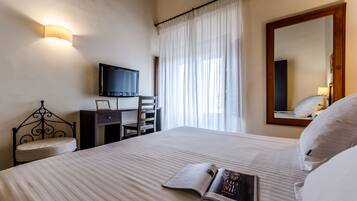 Une chambre d’hôtel équipée d’un lit, d’un bureau, d’une chaise, d’une télévision et d’un grand miroir.