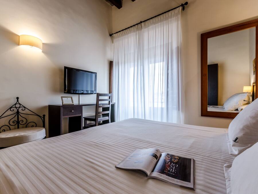 Une chambre d’hôtel équipée d’un lit, d’un bureau, d’une chaise, d’une télévision et d’un grand miroir.