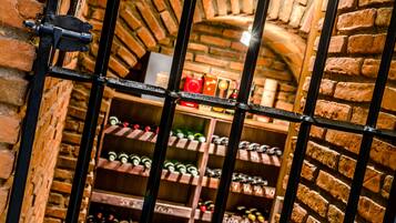 A brick-walled wine cellar with shelves of wine bottles.