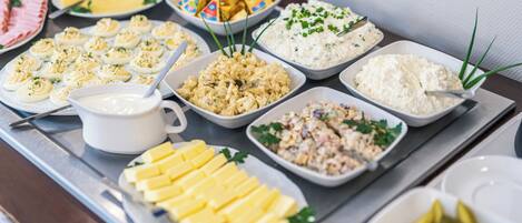 Una mesa de buffet con diversos platos, incluyendo huevos rellenos, ensalada de macarrones y queso.