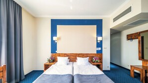 Habitación de hotel con dos camas, cabecera de madera, un espejo, un escritorio y una silla.
