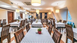 Un comedor amplio con manteles a cuadros, sillas de madera e iluminación colgante.