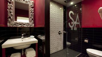 A bathroom with a white sink, a mirror with an ornate frame, a shower area, and a toilet.