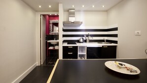Una cocina moderna con un salpicadero a rayas negras y blancas, una campana extractora de acero inoxidable y una encimera negra.