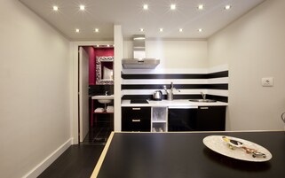 A modern kitchen with a black and white striped backsplash, a stainless steel range hood, and a black countertop.