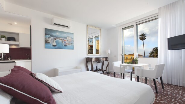 Habitación de hotel con una cama grande, un escritorio con silla, un televisor y un cuadro en la pared.
