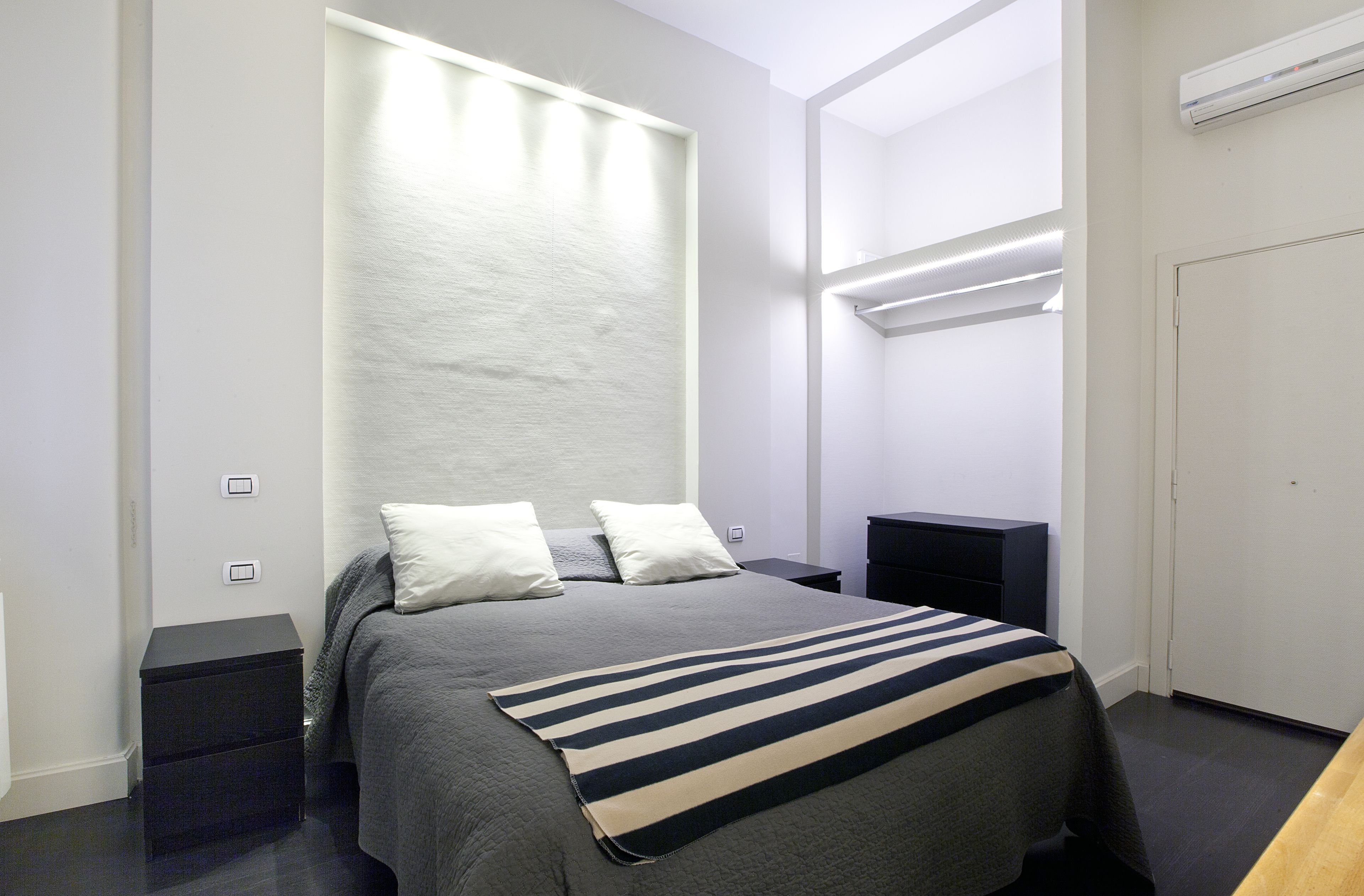 Un dormitorio moderno con cama, mesitas de noche y un armario.
