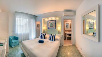 Ein Hotelzimmer mit Bett, Stuhl, Schreibtisch, Spiegel und einem durch eine offene Tür einsehbaren Badezimmer.