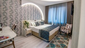 A modern hotel room with a neatly made bed, a dining area, and a patterned rug. - Dundar Hotel (Konya)