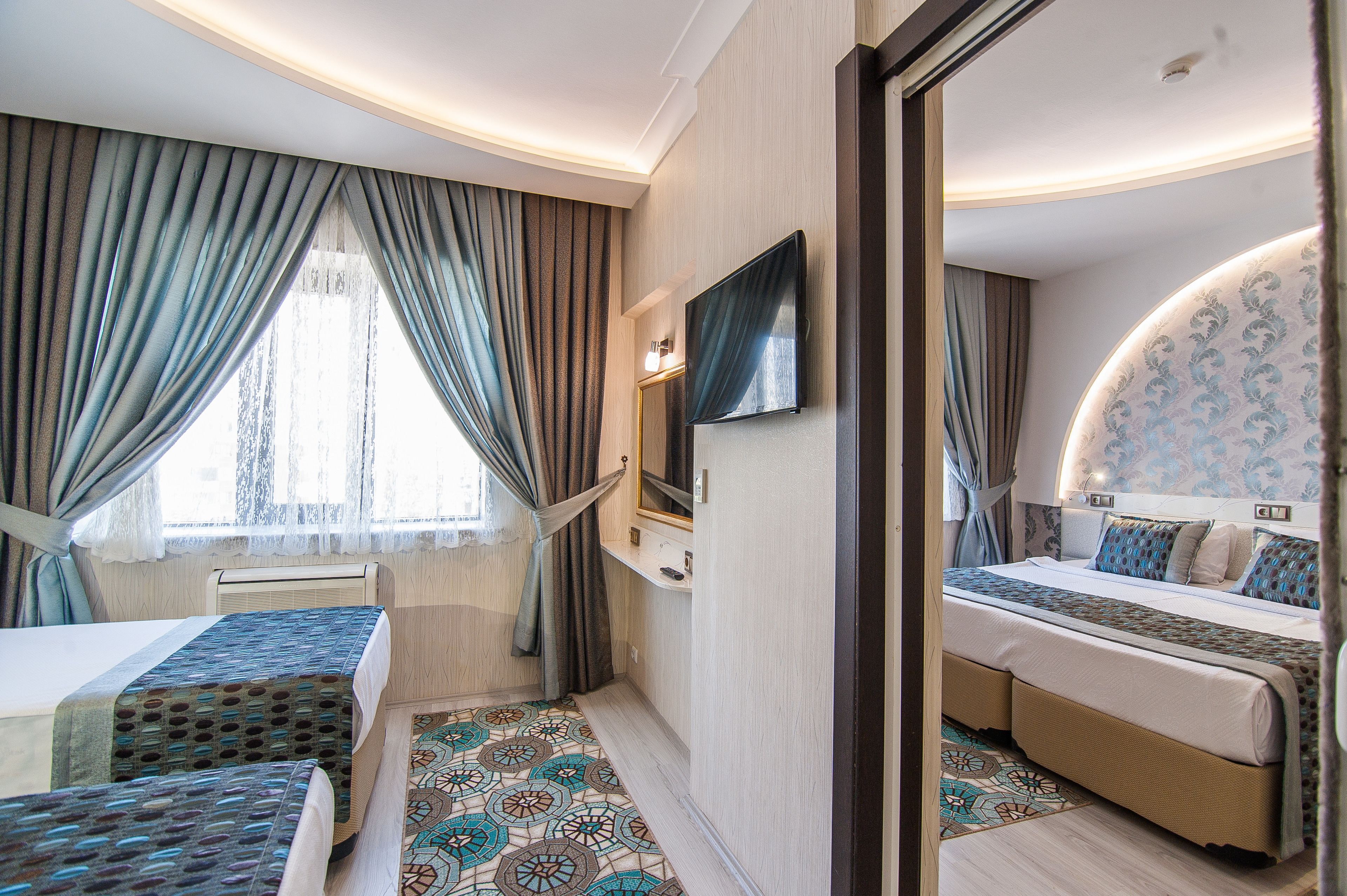 A hotel room with two beds, a TV, a mirror, and a patterned floor.