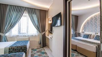 A hotel room with two beds, a TV, a mirror, and a patterned floor.