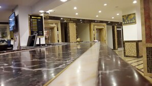 A hotel reception area with a marble counter, a lift sign, and a luggage room sign. - Dundar Hotel (Konya)