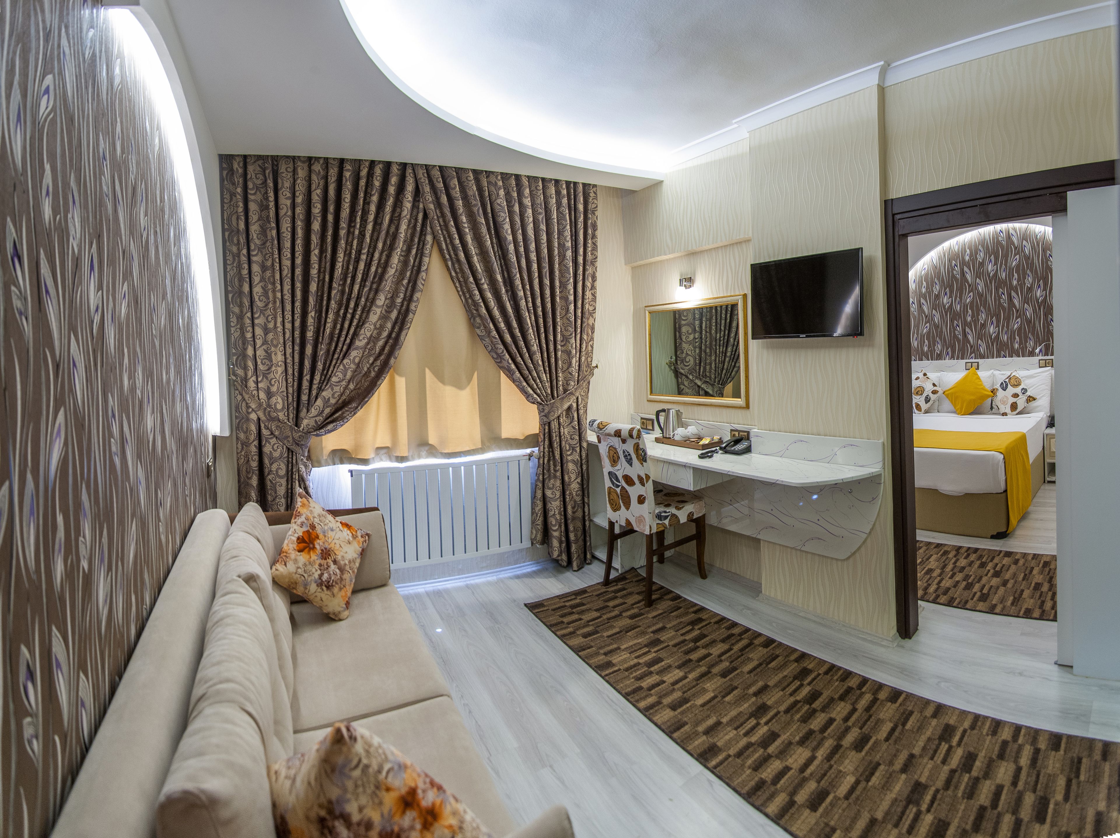 Een moderne hotelkamer met een bank, bureau, badkamer met spiegel en een televisie.