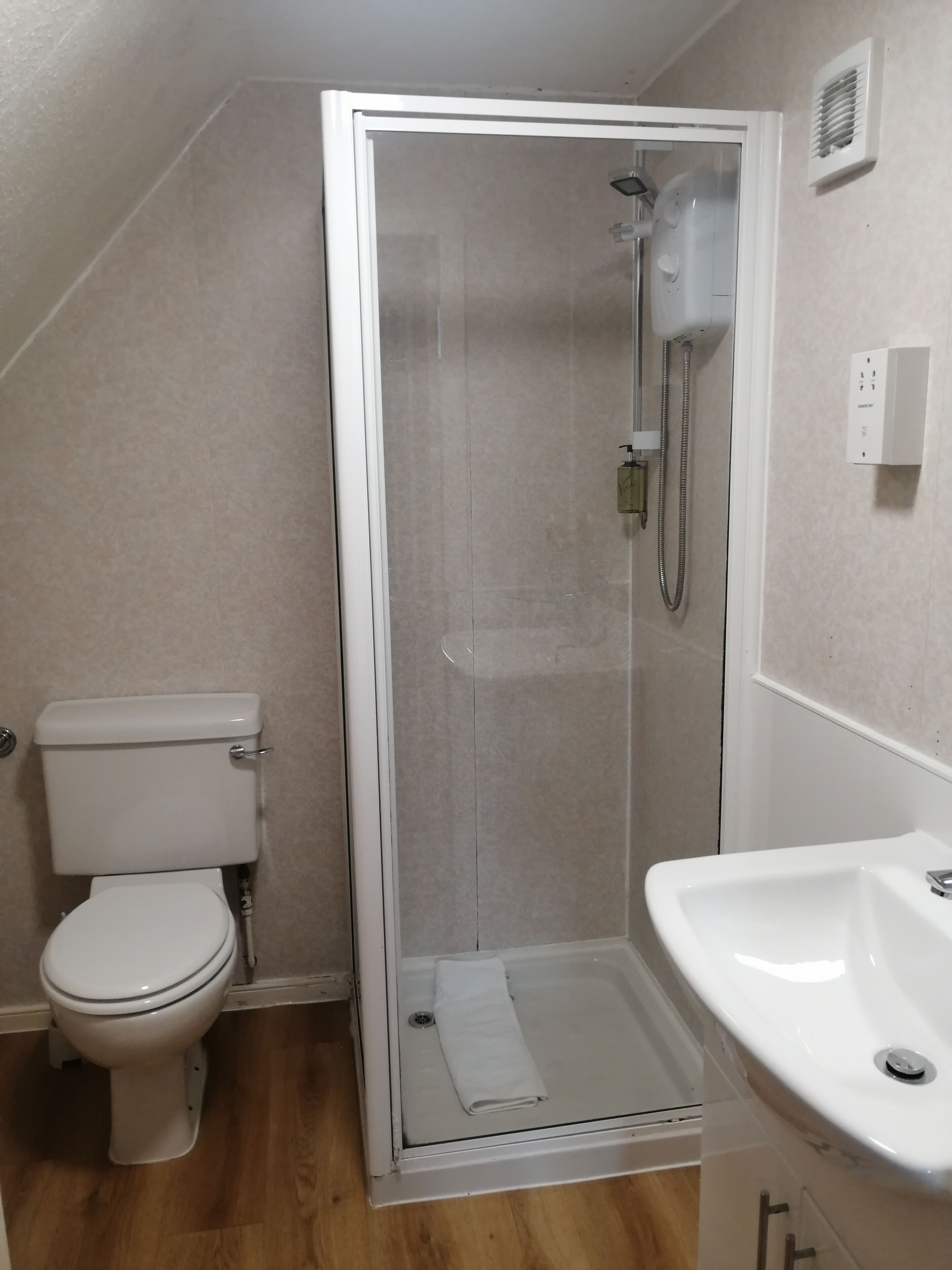 A bathroom with a toilet, a shower enclosure, and a sink.