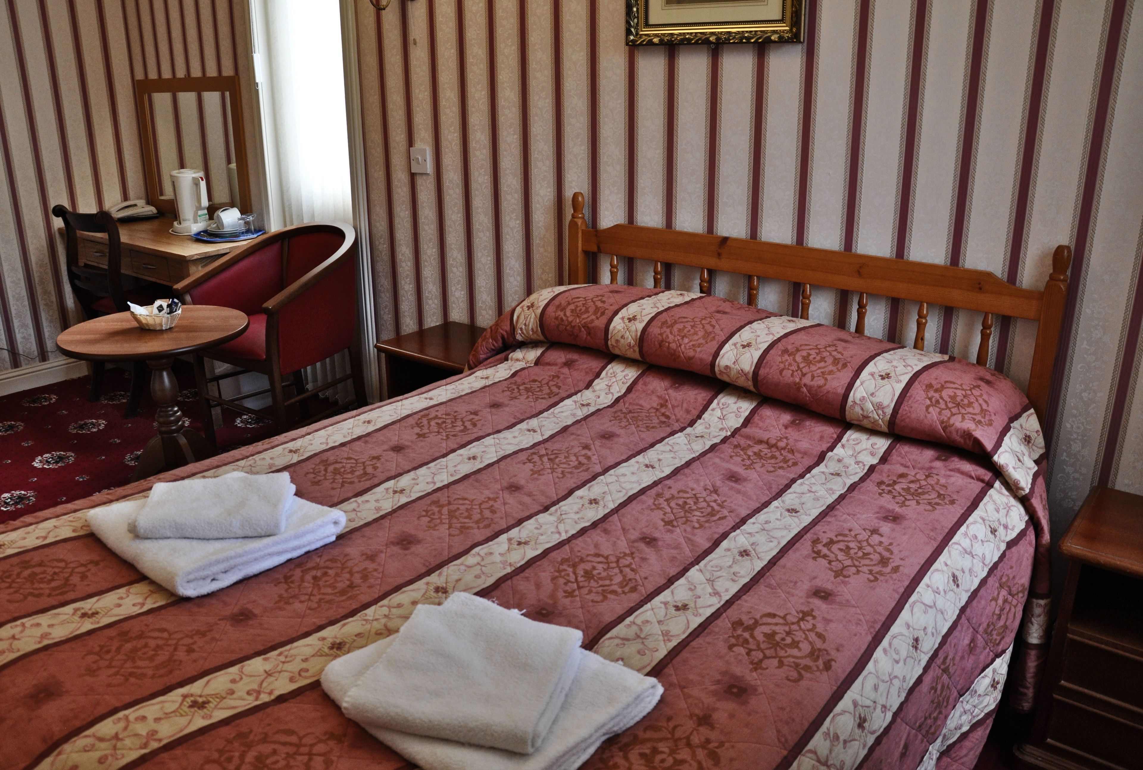 Hotellihuone, jossa on sänky, työpöytä, tuoli ja pieni pöytä.