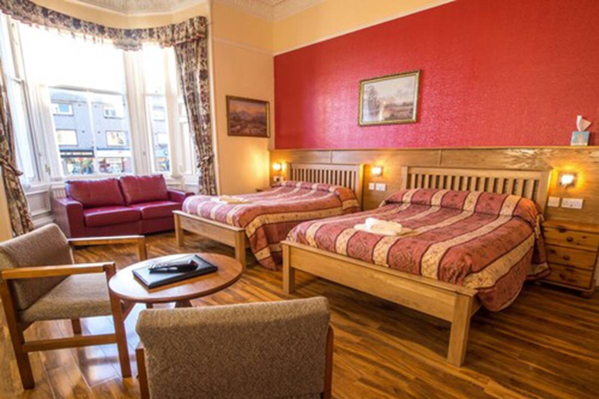 A hotel room with two beds, a sofa, a chair, and a small table.