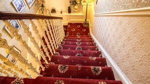 A grand staircase with ornate railings and a red carpeted floor. - Corstorphine Lodge (Edinburgh)