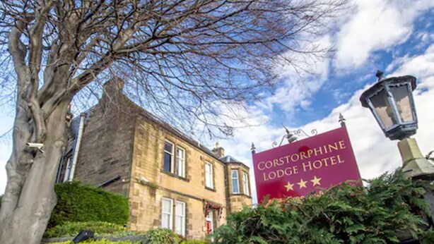 A historic building with a prominent red sign for the Corstorphine Lodge Hotel. - Corstorphine Lodge (Edinburgh)